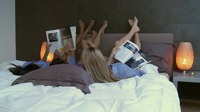 WS后视图的三个女人在床上与脚上，阅读杂志/布鲁塞尔，比利时视频下载