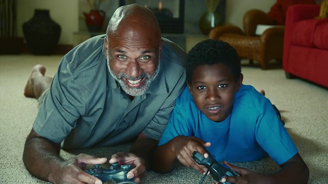 父亲和儿子(10-11)在客厅地板上玩电子游戏/ Bothell，美国华盛顿州视频素材