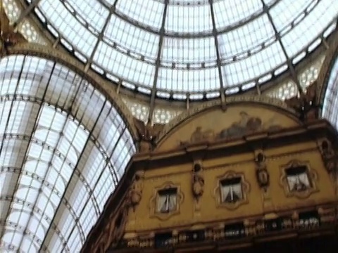 意大利米兰，Vittorio Emanuele II拱顶中央穹顶的低角度玻璃天花板/向下倾斜的长镜头行人走过普拉达商店视频下载