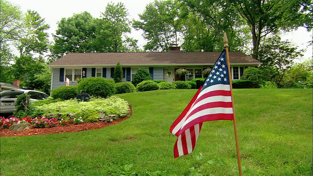 远景:近郊牧场房屋草坪上，微风中飘扬的美国国旗视频素材