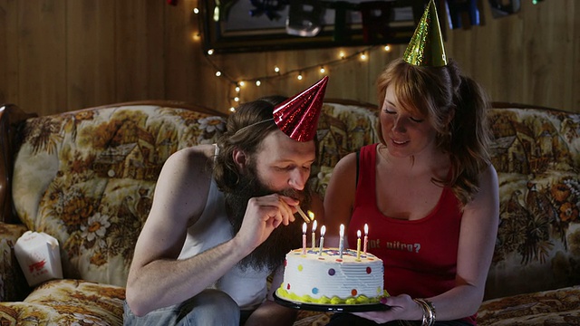 一对夫妇在客厅里庆祝一个男人的生日，一个男人正在抽烟/美国犹他州奥勒姆视频素材