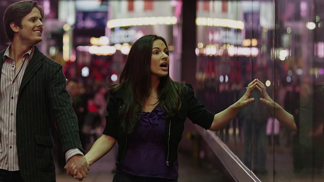 美国纽约州纽约，一对年轻夫妇在晚上看时代广场的橱窗视频下载