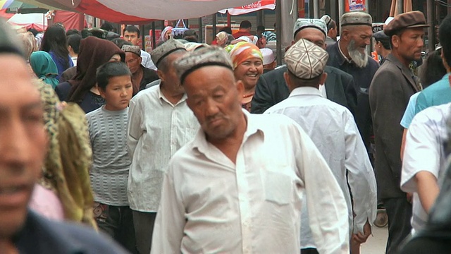 中国新疆喀什，男人和女人走过星期天市场视频下载
