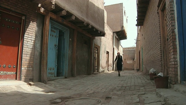 中国新疆喀什，一名妇女走过老城街道的小巷视频下载