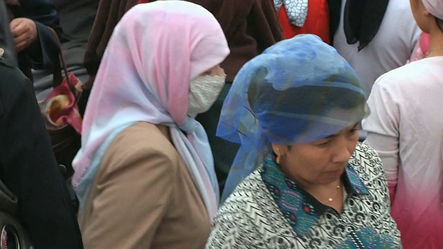 中国新疆喀什，穿着传统维吾尔服装的妇女走过市场视频下载