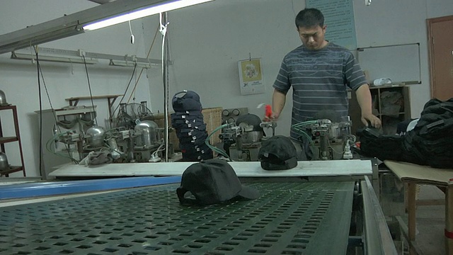 工厂工人将棒球帽扔到传送带上/江苏扬州视频下载