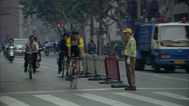 骑自行车的人和骑摩托车的人穿过十字路口/上海视频下载
