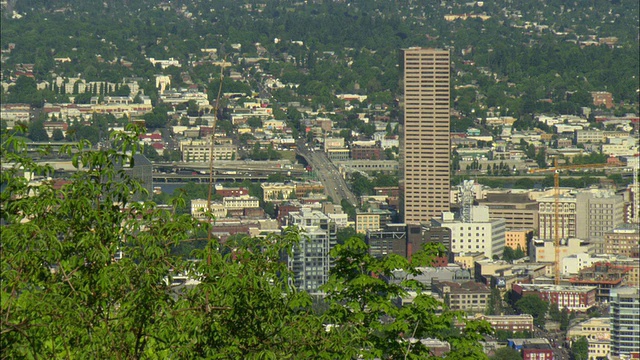从附近的绿色山坡上看到的波特兰城市，前景中有绿色的树木/俄勒冈，美国视频素材