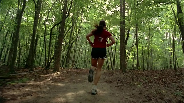 跟在一个女人后面跑过森林/红顶山州立公园，乔治亚州视频素材