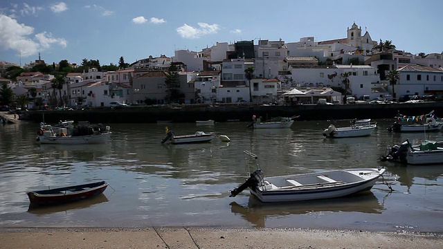 葡萄牙，阿尔加维，费拉古多，渔船停泊在港口，背景是城市景观视频素材