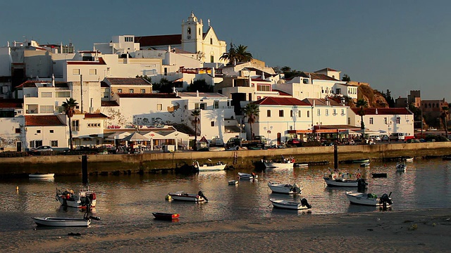 夕阳西下的WS小镇景观，渔船停泊在葡萄牙阿尔加维费拉古港的前景视频素材