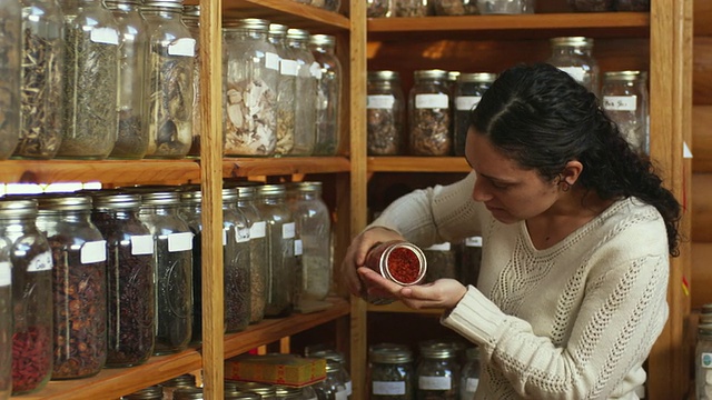 美国佛蒙特州曼彻斯特的MS Herbalist从商店货架上的罐子里嗅草药视频下载
