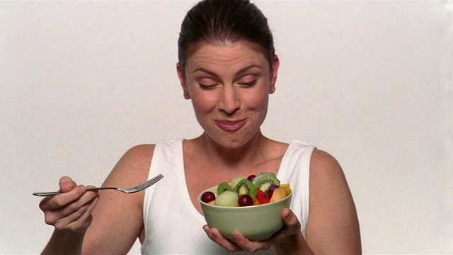 中杯的女人正从碗里吃水果沙拉视频素材