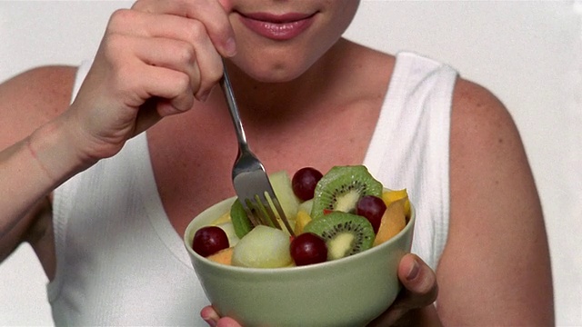 近距离倾斜的女人从碗里吃水果沙拉视频素材