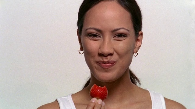 近距离女子咬草莓和微笑的镜头视频素材