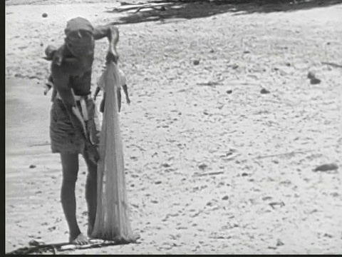 1949年，马绍尔群岛，当地男子在海滩上扔渔网，抓小鱼，而男孩们在看/ Likiep视频下载