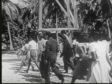 1949年B/W蒙太奇人在户外塔上摇铃，当地人走向和进入简单的木制教堂。牧师在讲坛上朗读。用马绍尔群岛语言书写的圣经CU页。马绍尔群岛的利基普岛视频下载
