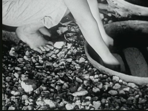 1949年蒙太奇妇女从地面烤箱中取出面包，马绍尔群岛视频下载