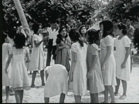 1949年B/W蒙太奇圆圈的年轻女孩玩游戏，用一只手耍小椰子。他们为胜利者/马绍尔群岛的Likiep鼓掌视频下载