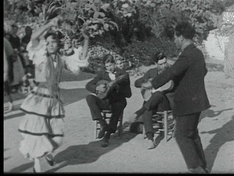 1925年，西班牙格拉纳达，吉普赛男子和女子在跳弗拉明戈舞，后面有两位音乐家坐在椅子上演奏视频素材