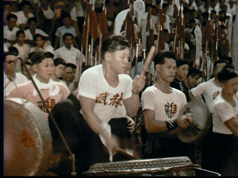 1957年，蒙太奇男子在仪式的中国狮子服装跳舞模拟战斗，而观众观看。鼓手敲打大鼓/棍棒+脚/新加坡/音频视频素材