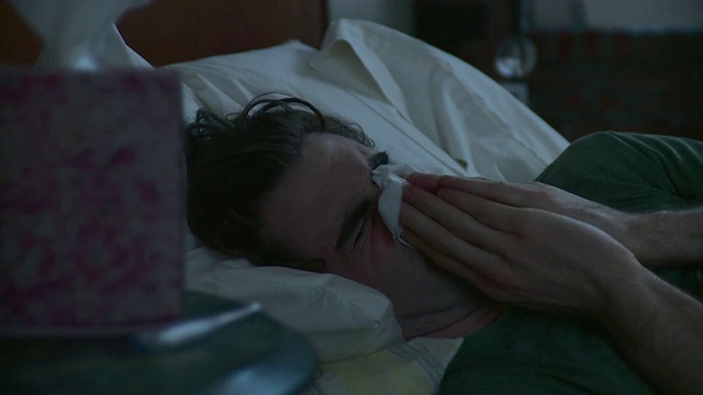 CU生病的年轻人躺在床上，从边桌上拿纸巾擤鼻涕/美国纽约布鲁克林视频下载