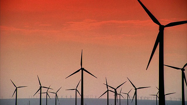 SLO MO WS PAN日落时橙色天空下风力涡轮机的剪影/ Junction，美国德克萨斯州视频素材