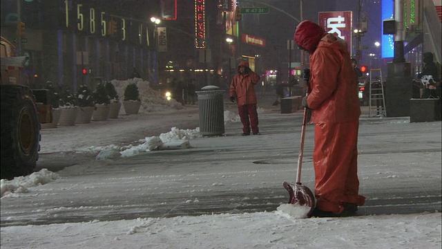 WS PAN Man在麦迪逊大道在下雪的夜晚铲人行道/纽约，美国视频下载