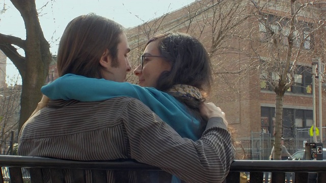 美国新泽西州泽西城，一对年轻夫妇坐在长椅上接吻视频素材