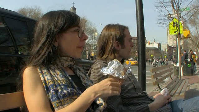 一对年轻夫妇在美国新泽西州纽约市中心/泽西城的长椅上吃沙拉三明治视频素材
