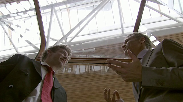 英国伦敦一幢写字楼里，两名商人在电梯里交谈视频素材