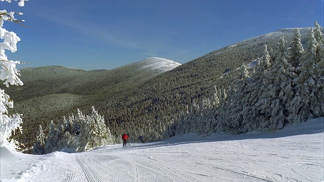 一对夫妇在新英格兰传统的积雪滑雪坡上滑雪/兰吉利，缅因州，美国视频素材