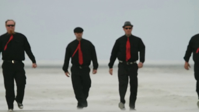 四个穿着黑色衣服，打着红色领带的男人走过美国佛罗里达州的杰克逊维尔海滩视频下载