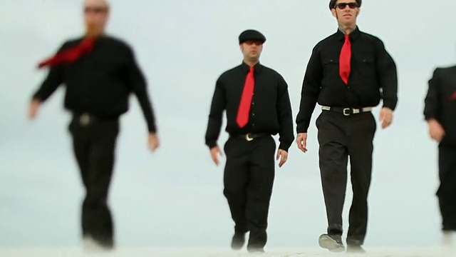 SLO MO WS LA四名穿着黑色衣服和红色领带的男子走过海滩/杰克逊维尔，美国佛罗里达视频下载