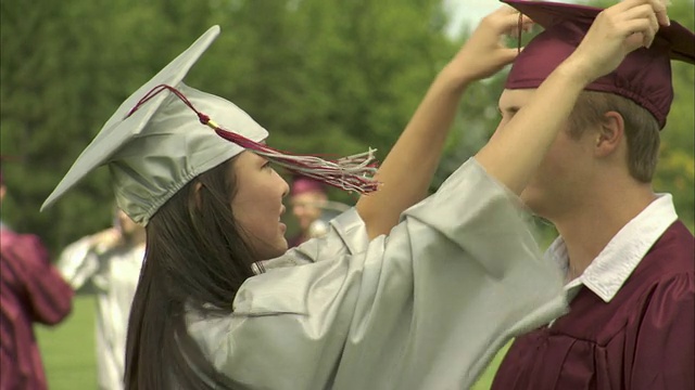 两位高中毕业生(17-19岁)调整彼此的帽子，对着镜头微笑/美国威斯康星州阿普尔顿视频素材
