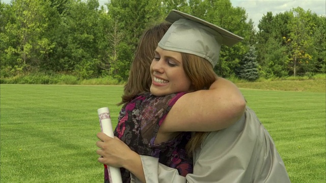母亲抱着穿着毕业礼服的女儿，拿着毕业证书/美国威斯康星州阿普尔顿视频素材