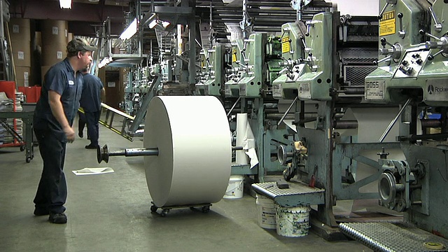 美国密歇根州鲍尔斯印刷厂的WS人在印刷机上添加新闻纸卷视频下载