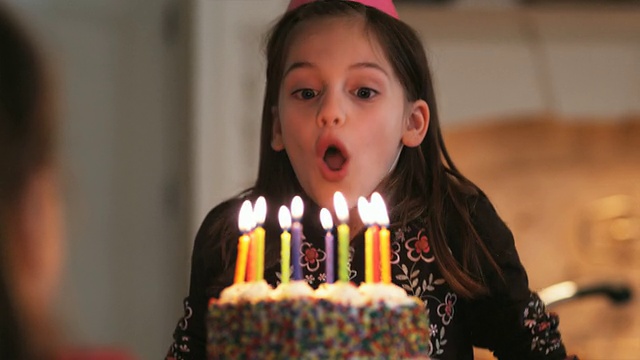 小女孩吹灭生日蛋糕上的蜡烛视频素材
