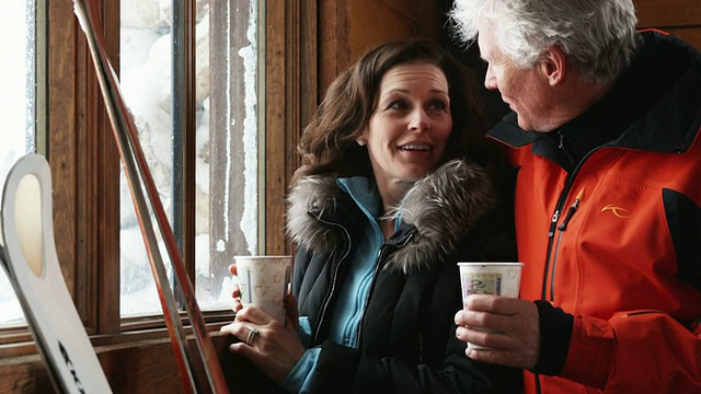 一对成年夫妇在滑雪胜地的小屋边喝咖啡边看窗外视频下载