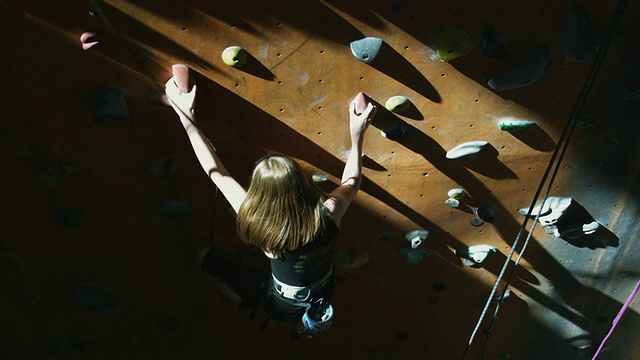 一名年轻女子在爬室内攀岩墙视频素材