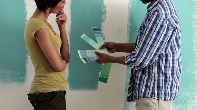 夫妇俩比较色板和墙上的油漆视频下载