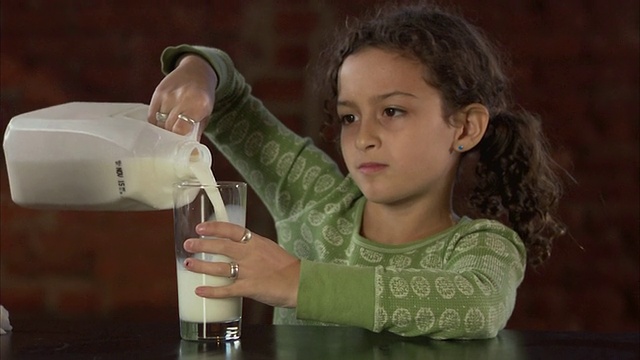 女士(8-9)倒牛奶并洒出来/泽西城，新泽西，美国视频下载