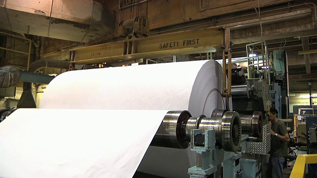 在美国密歇根州造纸厂，铜板工人修剪新纸卷，用机械提升机移动视频下载