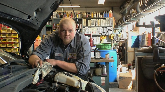 MS ZI汽车机械师在美国密歇根州切尔西汽车修理厂擦拭发动机室的机油和油脂视频下载