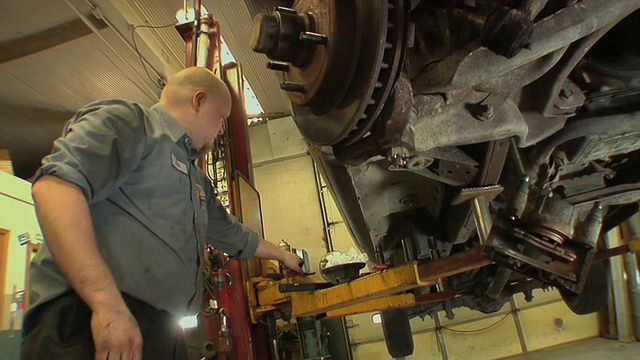 美国密歇根州切尔西汽车修理厂，汽车技师使用钳子将螺母固定在汽车车轮上视频下载