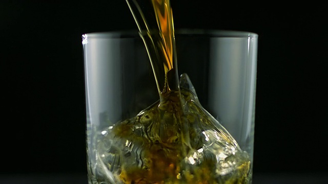 SLO MO MS Studio在黑色背景下将威士忌倒入装有冰块的玻璃杯中视频下载