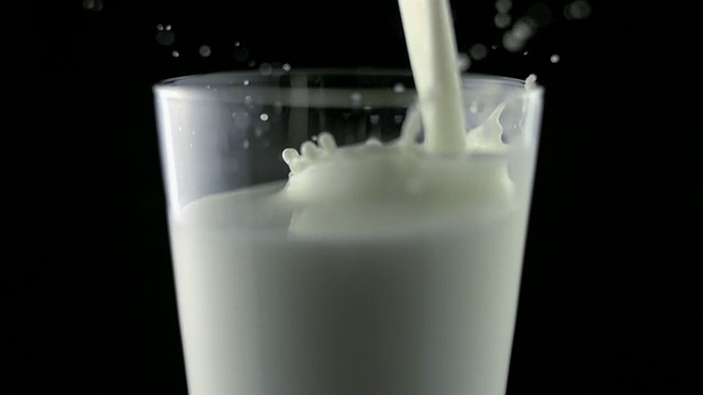 SLO MO MS Studio拍摄了在黑色背景下将牛奶倒入玻璃杯中的画面视频素材