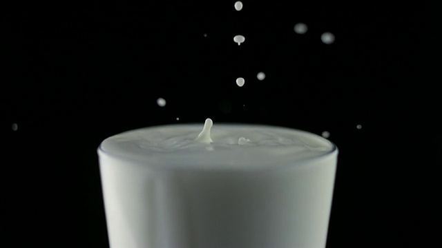 SLO MO CU Studio在黑色背景上拍摄了牛奶滴落入满杯的画面视频素材