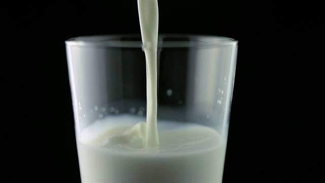 SLO MO MS Studio拍摄了在黑色背景下将牛奶倒入玻璃杯中的画面视频素材