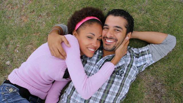 一对年轻夫妇躺在草地上，互相摩擦脸颊，微笑着/古巴哈瓦那视频下载